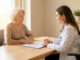 Une femme senior échange sereinement avec une médecin dans un cabinet lumineux, avec un dossier médical fermé sur le bureau.