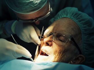Chirurgien-dentiste réalisant une greffe de gencive sur un patient en cabinet dentaire.