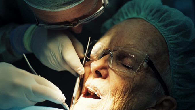 greffe-de-la-gencive-cohml7 Chirurgien-dentiste réalisant une greffe de gencive sur un patient en cabinet dentaire.